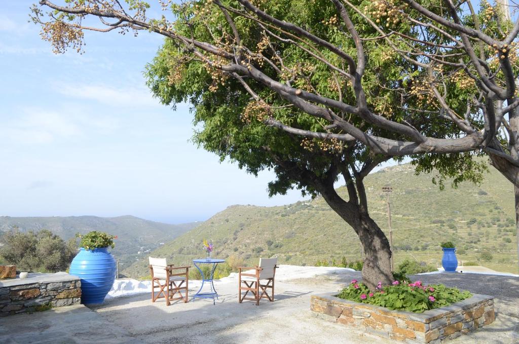 a patio with a tree and chairs and a table at Traditional Farmhouse in Kea in Pisses