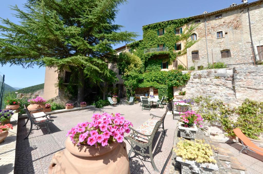 un patio con sedie e fiori di fronte a un edificio di La Torre Del Cerreto a Cerreto di Spoleto