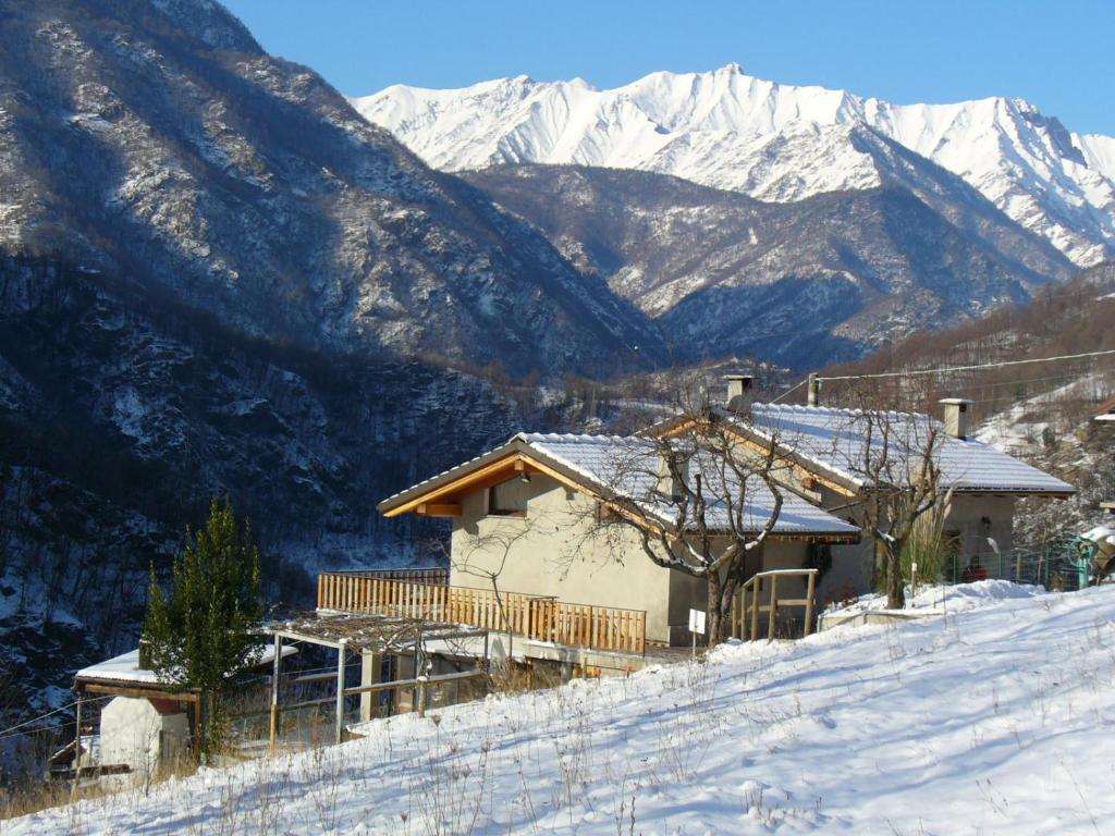 una casa en una colina nevada con montañas en el fondo en Il Girasole, en Perrero