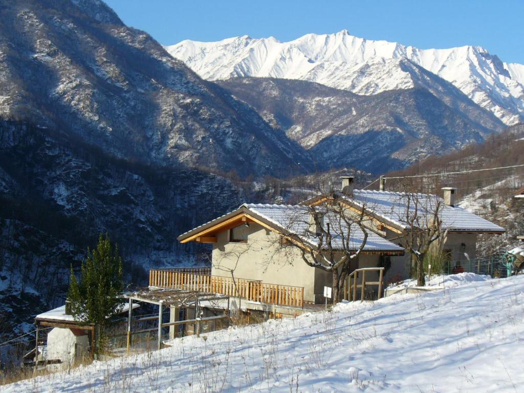 a house on a snowy hill with mountains in the background at Il Girasole in Perrero