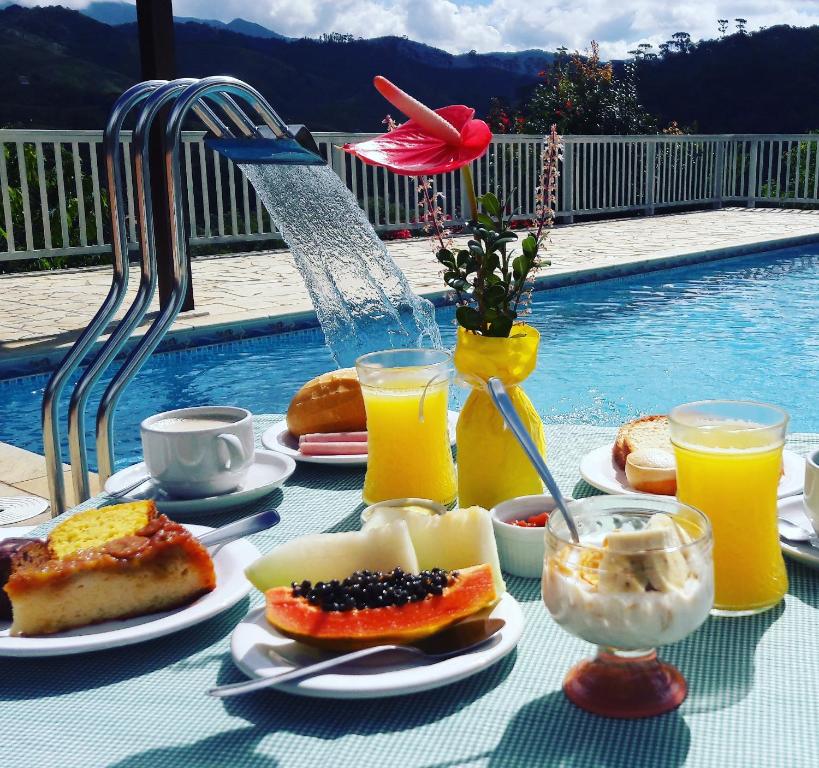 a table topped with plates of food and orange juice at Pousada Canário Da Terra in Visconde De Maua