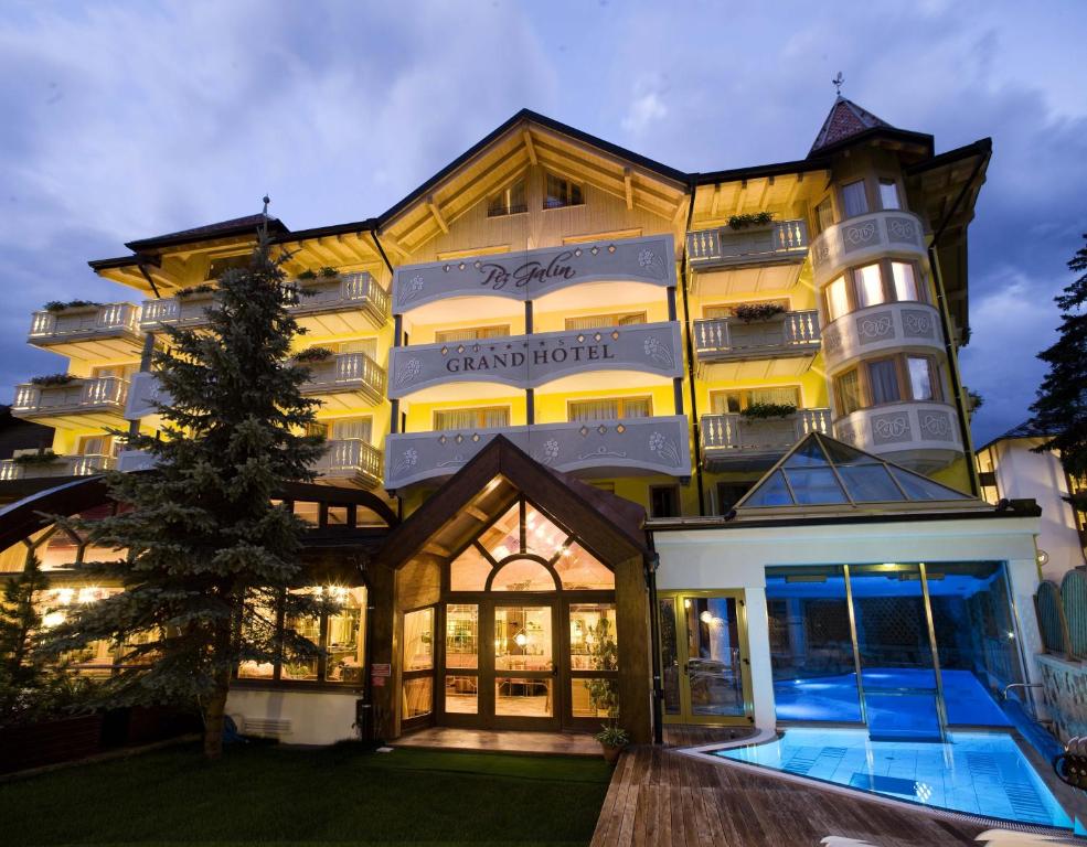 a large building with a swimming pool in front of it at Piz Galin Grand Hotel Family & Wellness in Andalo