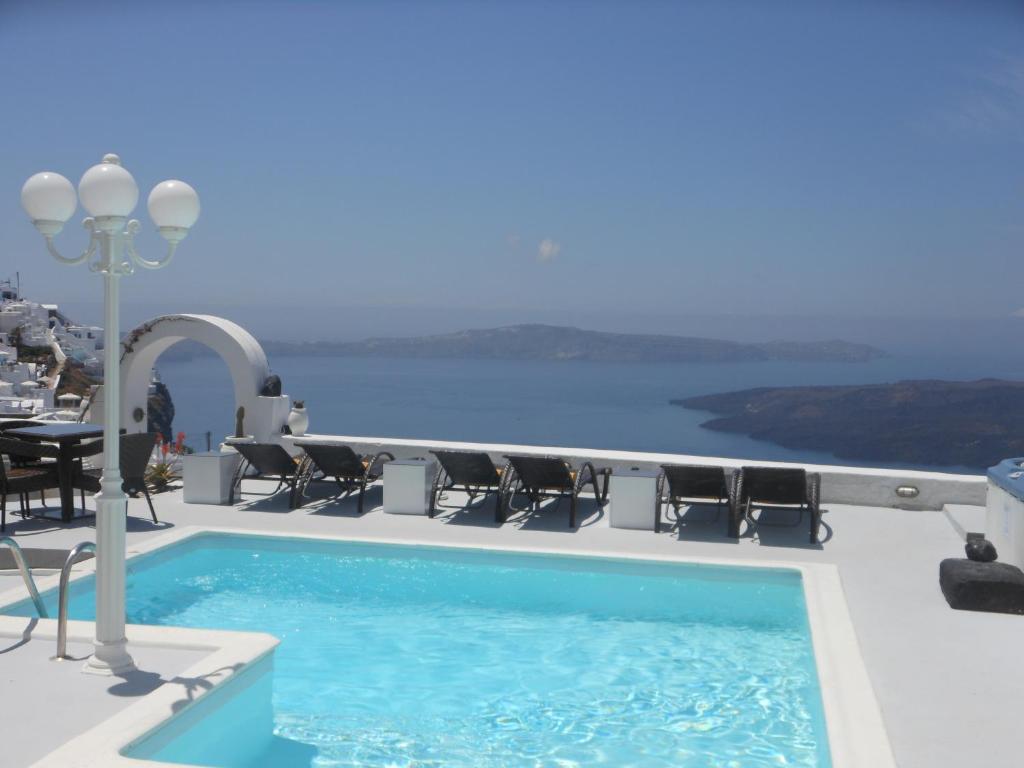 a pool on the roof of a hotel with a view of the ocean at Nomikos Villas in Fira