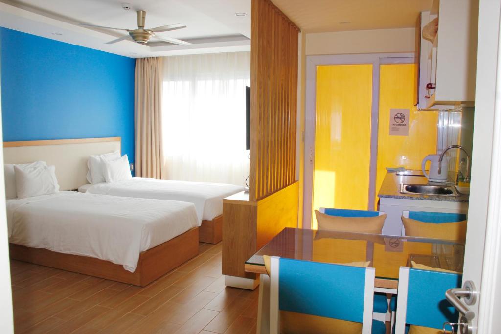 a bedroom with two beds and a table and a kitchen at BX Apartment in Nha Trang