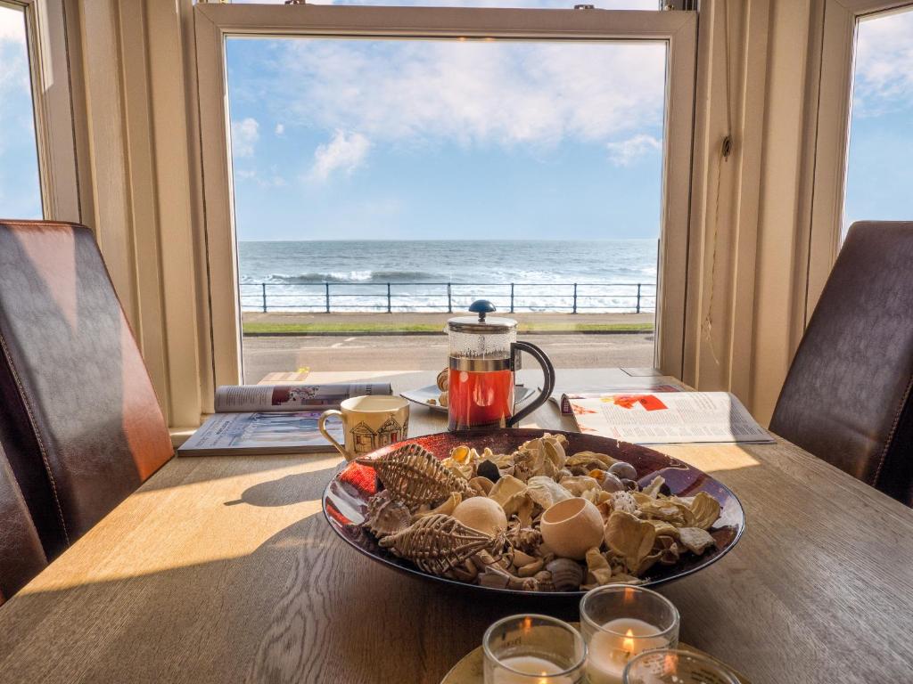 a plate of food on a table with a view of the ocean at St Kitts Holiday Apartment in Filey