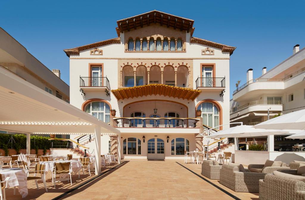 um grande edifício com mesas e cadeiras em frente em Hotel Casa Vilella 4* Sup em Sitges