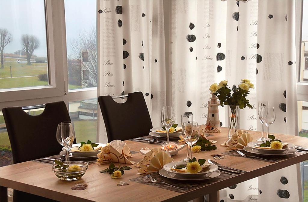 einen Holztisch mit Teller mit Speisen und Weingläsern in der Unterkunft Apartment Leuchtturm 16 in Großenbrode