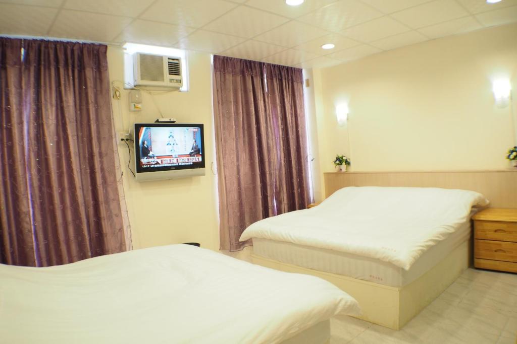 Habitación de hotel con 2 camas y TV en Sun Moon Star Hostel en Budai