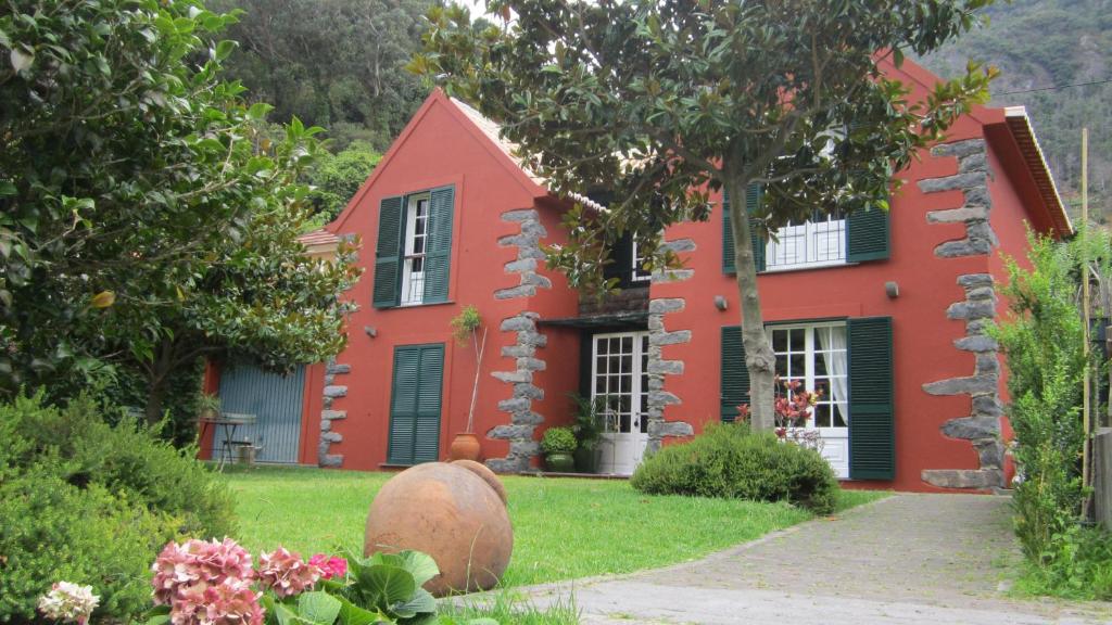 een rood huis met een boom ervoor bij Palheirinho da Camélia in São Vicente