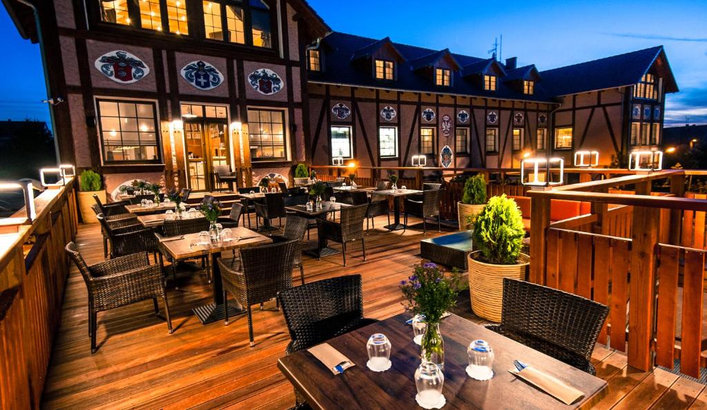 un restaurant avec des tables et des chaises sur une terrasse en bois dans l'établissement Akademia Kuraszków, à Kuraszków