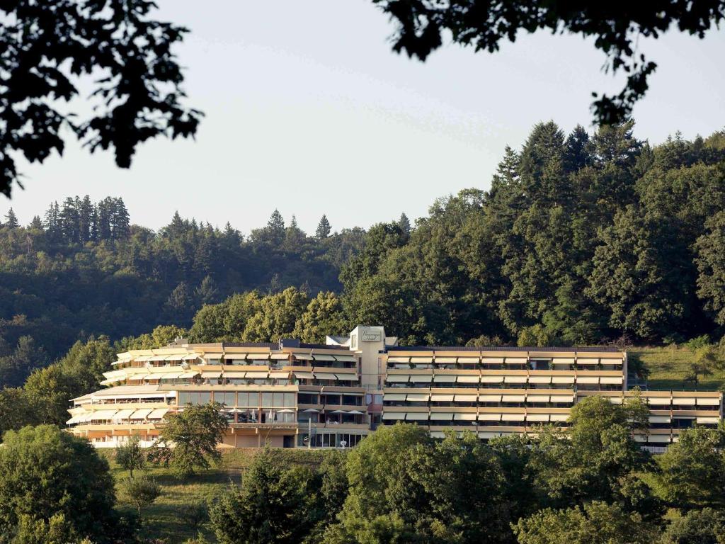 un grand bâtiment au milieu d'une forêt dans l'établissement Mercure Hotel Panorama Freiburg, à Fribourg-en-Brisgau