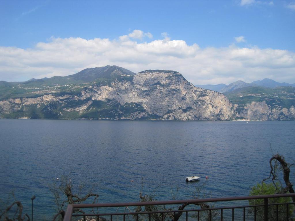 a boat in a large body of water with mountains at La Virgola Apartments in Brenzone sul Garda