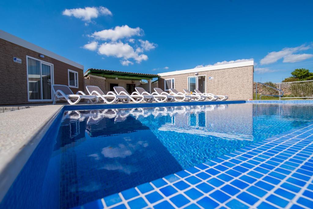 a swimming pool with chairs and a swimming pool at Mobile Homes Residence Ulika in Krk