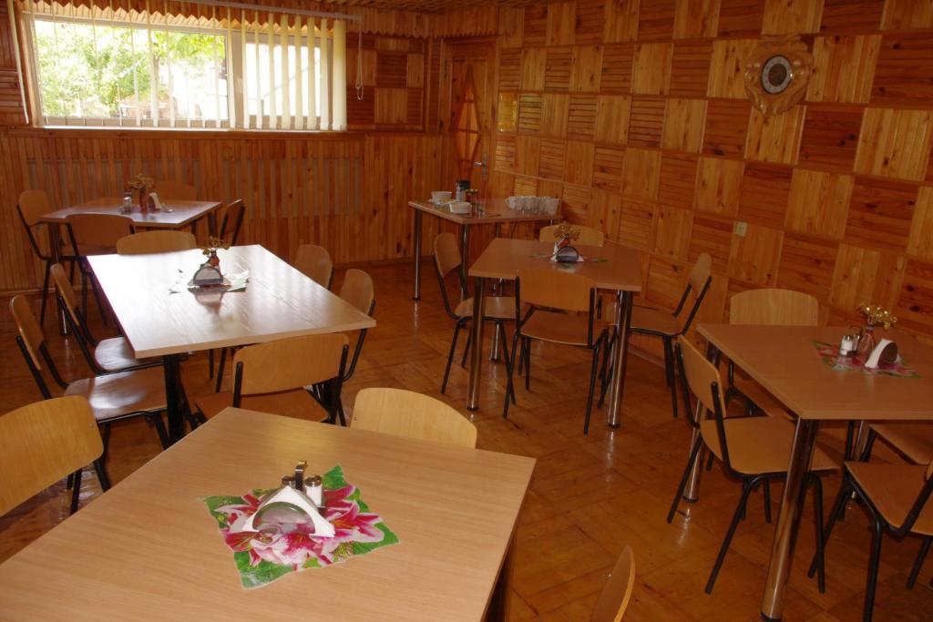 un restaurante con mesas y sillas con flores. en Turnė Guest House, en Šiauliai