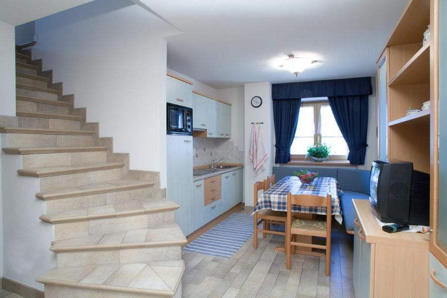 a living room with a staircase and a kitchen with a table at Santin Apartments in Livigno