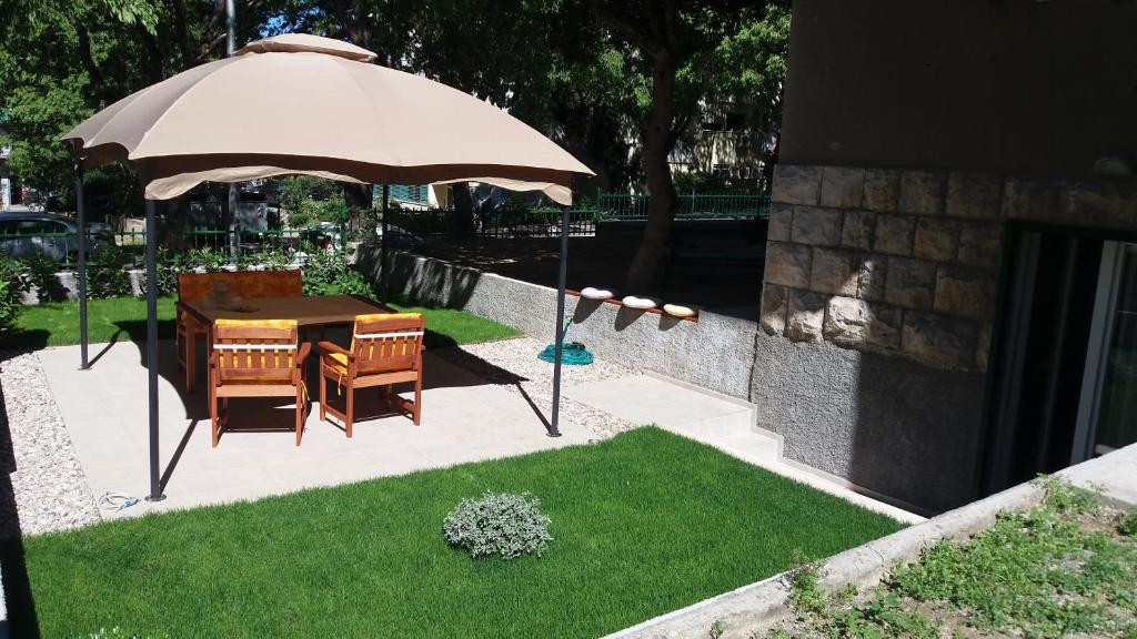 a table and chairs under an umbrella in a yard at Garden apartment Vanya in Split