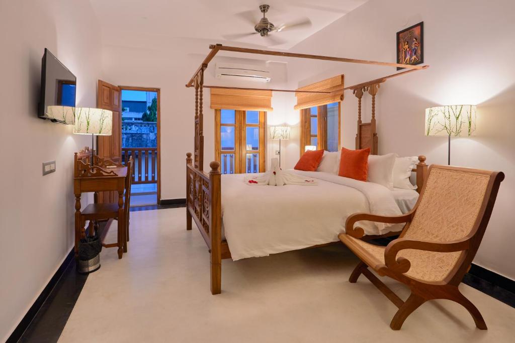 a bedroom with a large bed and a chair at Villa Krish in Puducherry