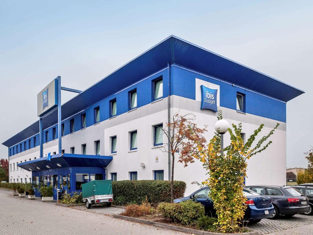 un gran edificio azul y blanco con coches aparcados en un aparcamiento en ibis budget Wiesbaden Nordenstadt, en Wiesbaden