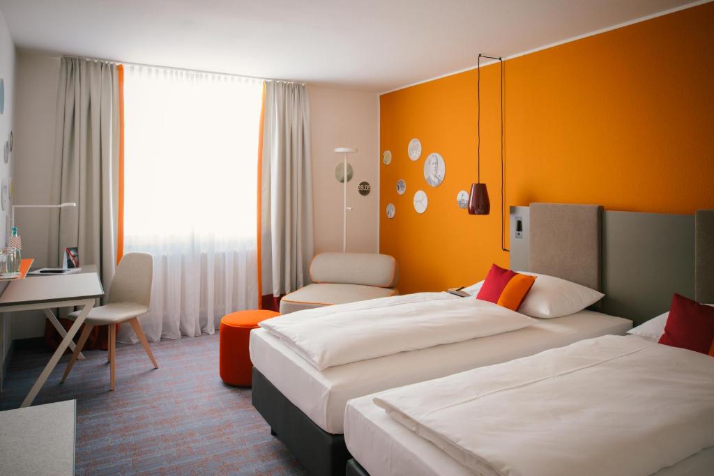 a hotel room with two beds and a desk at Vienna House Easy by Wyndham Trier in Trier