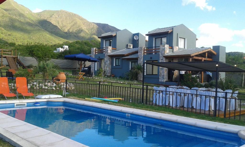 una casa con piscina frente a una casa en Cabañas Refugio Uritorco en Capilla del Monte