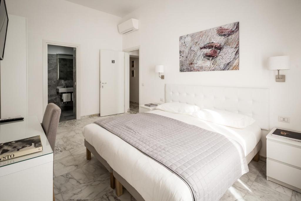 a white bedroom with a bed and a kitchen at Vinci House in Rome