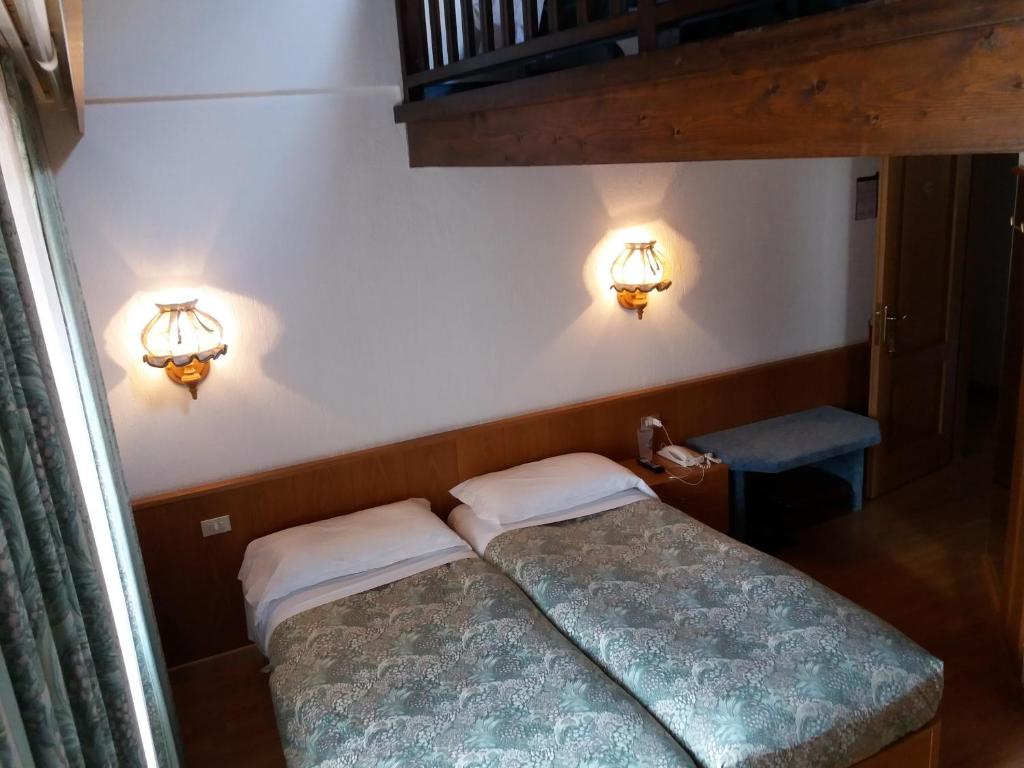 two beds in a small room with lights on the wall at Hotel Ottoz Meublé in Courmayeur