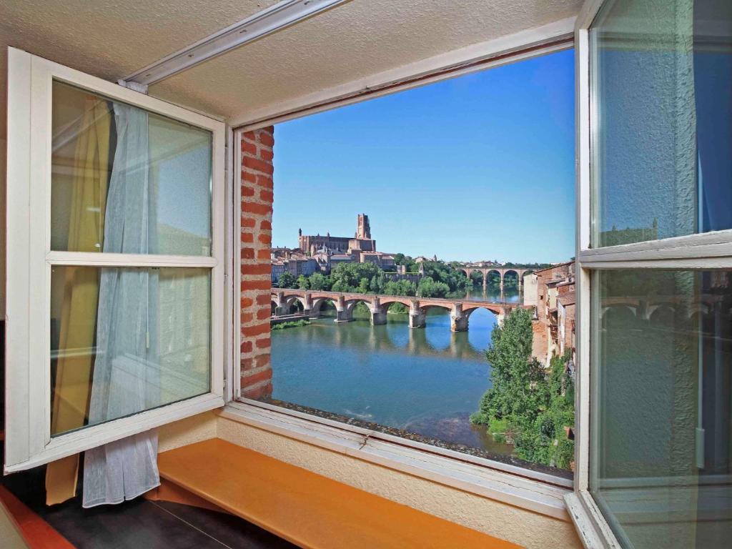 a window with a view of a river and bridge at Mercure Albi Bastides in Albi