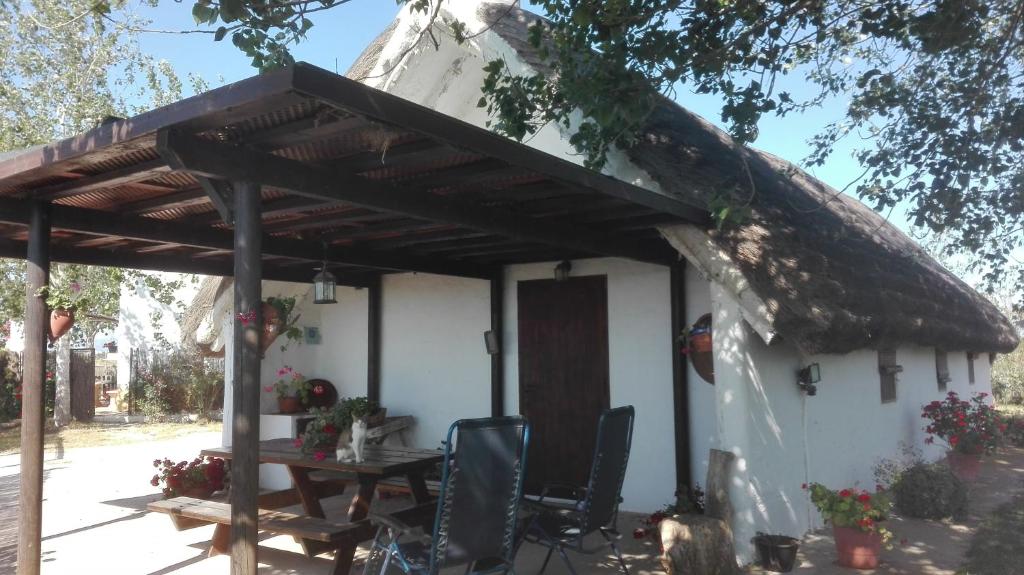 uma casa com um telhado de palha e uma mesa e cadeiras em La Barraca d'en Salvador em Deltebre