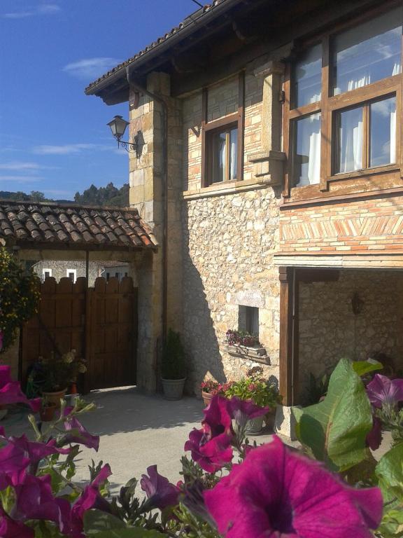 a stone house with a gate and purple flowers at Posada El Salin in Muñorrodero