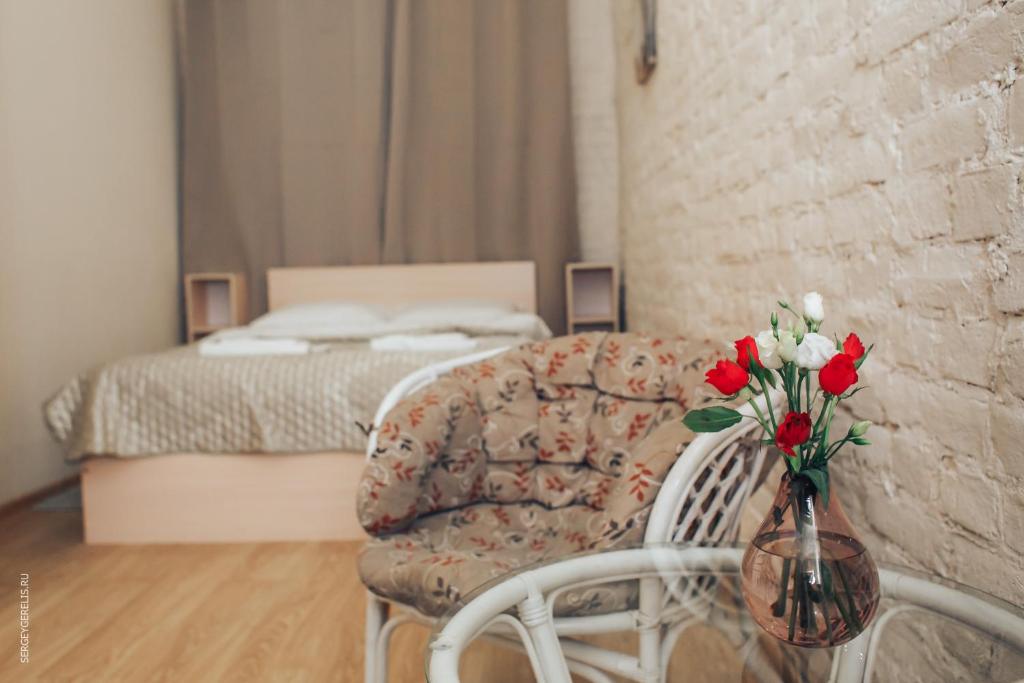 a bedroom with a couch and a table with a vase of flowers at Tihiy dvorik in Saint Petersburg