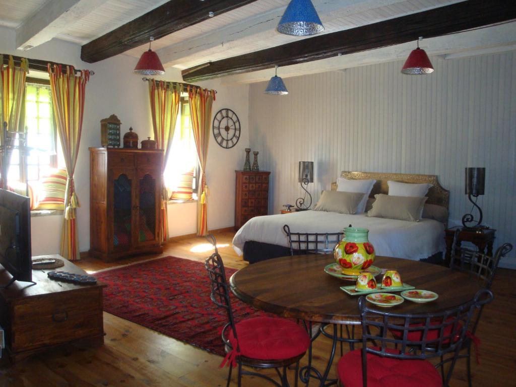 Schlafzimmer mit einem Bett, einem Tisch und einem Bett in der Unterkunft D'Ici et D'Ailleurs in Cordes-sur-Ciel