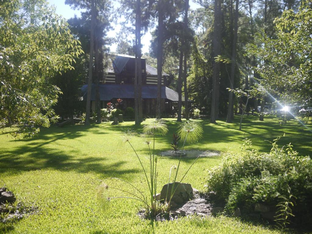 une maison au milieu d'une pelouse avec des arbres dans l'établissement Ñande Retá, à Colonia Carlos Pellegrini