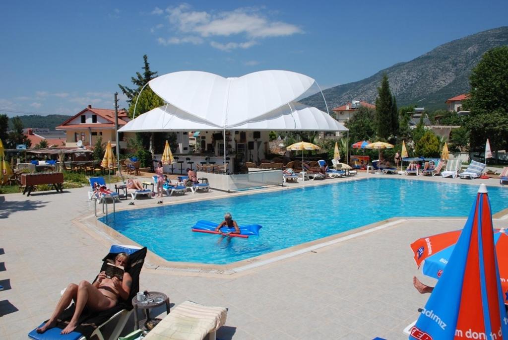 una mujer tendida en sillas en una piscina en Ant Apart Hotel, en Ölüdeniz