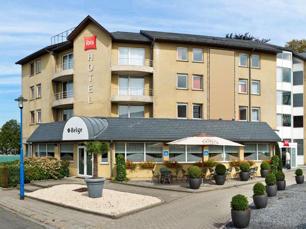 a hotel building with tables and chairs in front of it at ibis Hotel Brussels Expo Atomium in Brussels