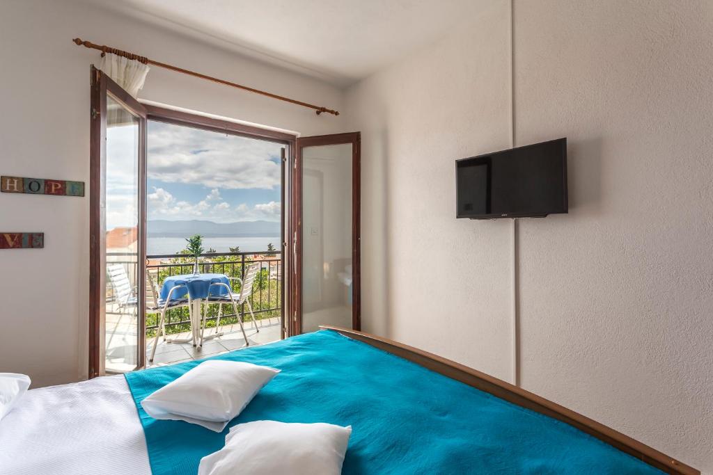 a bedroom with a blue bed with a balcony at Apartmani Bezma in Bol