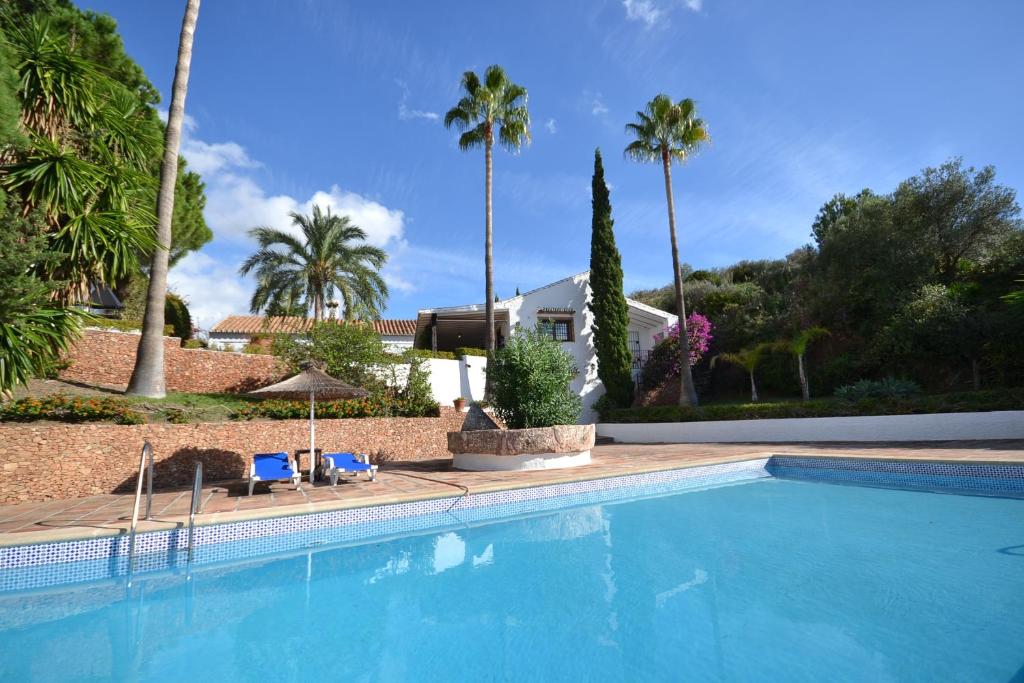 una piscina con palmeras y una casa en Molino Casanova Menyber, en Nerja