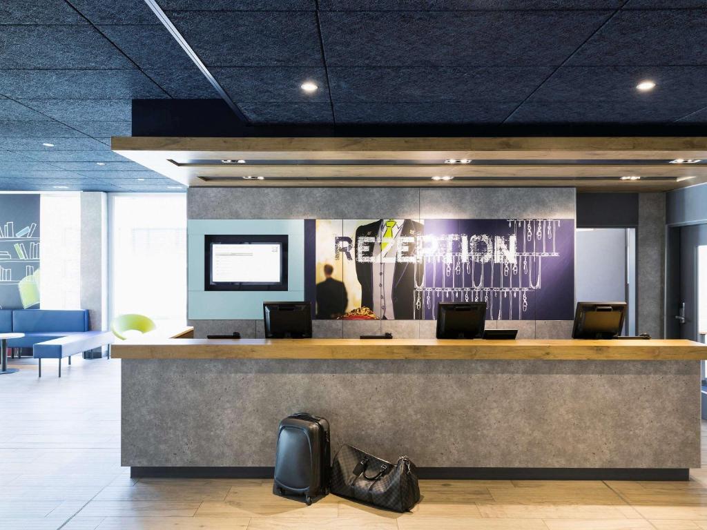 a lobby with a reception counter with shoes on the floor at ibis budget Zurich Airport in Glattbrugg