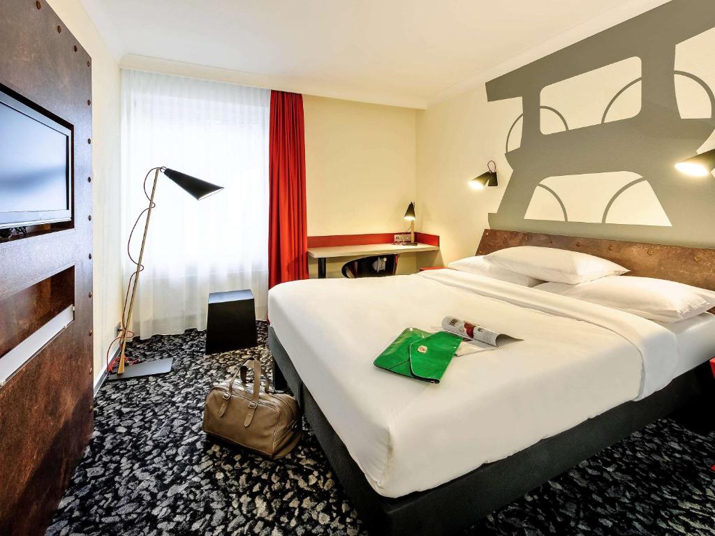 una habitación de hotel con una cama grande con una bolsa verde. en Hotel am Schlosspark Herten, en Herten