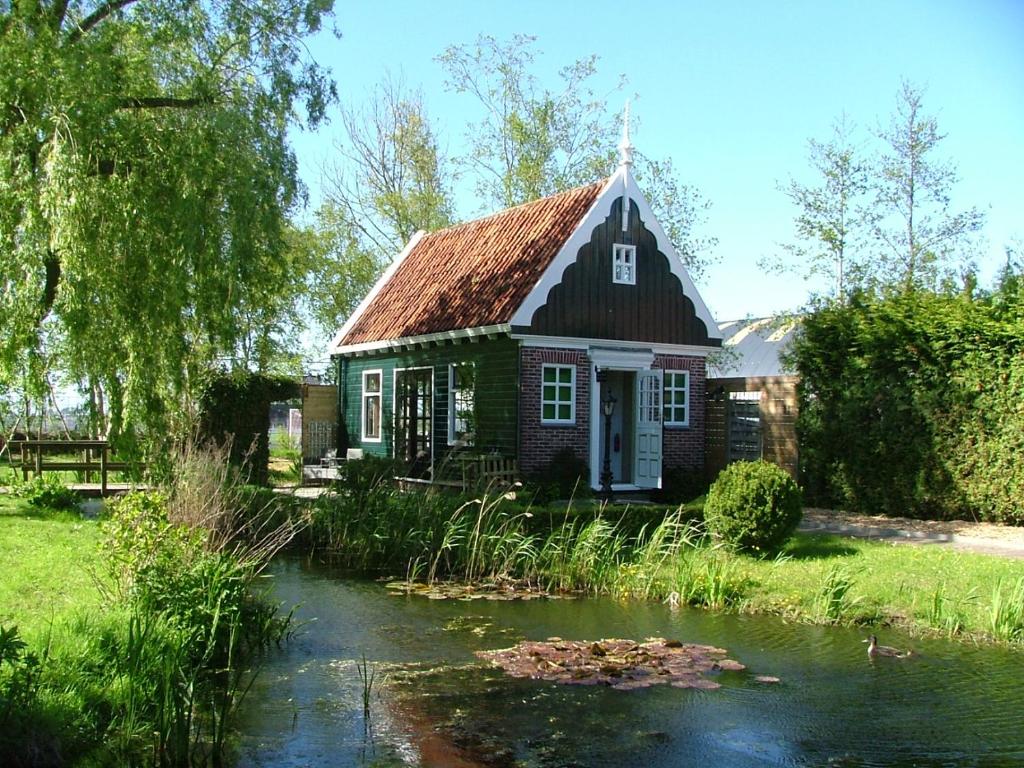 una pequeña casa con un estanque delante en B&B Saense huisje, en Assendelft