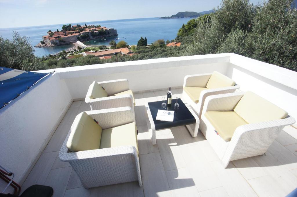 a balcony with white chairs and a table and the ocean at Vila Mitrovich in Sveti Stefan