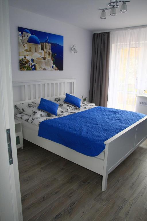 a bedroom with a bed with a blue comforter at Andros Apartamenty Świnoujście in Świnoujście