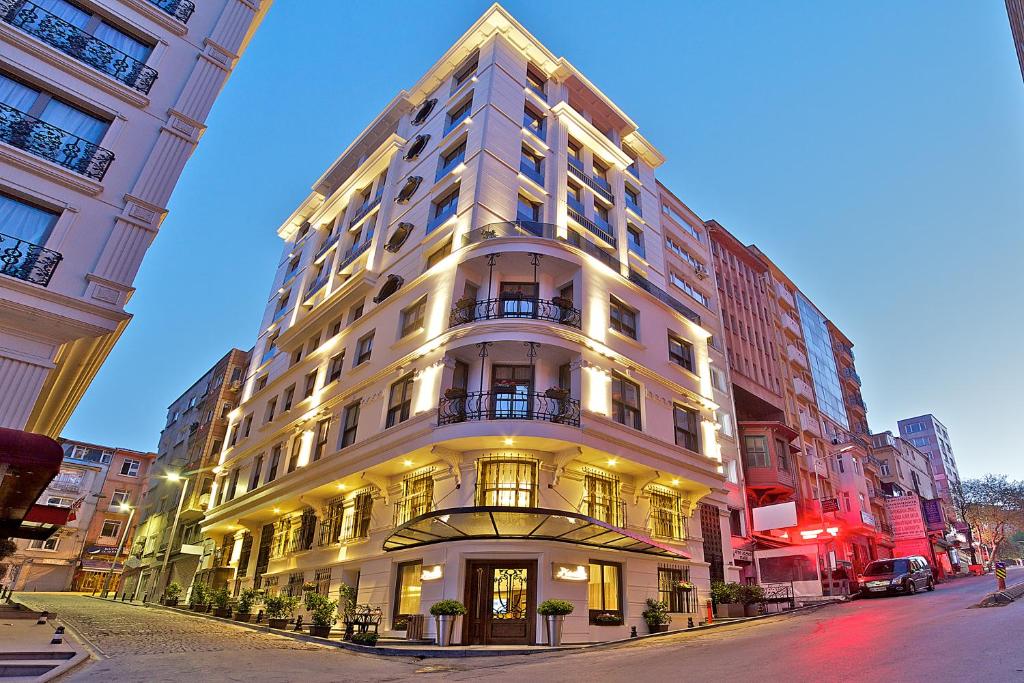 ein hohes weißes Gebäude in der Nacht auf einer Stadtstraße in der Unterkunft Adelmar Hotel Istanbul Sisli in Istanbul