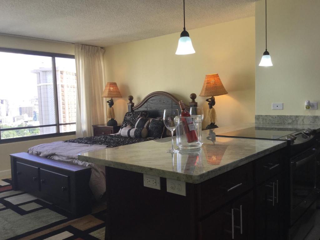 a bedroom with a bed and a kitchen with a counter at Waikiki Ala Moana Studio in Honolulu