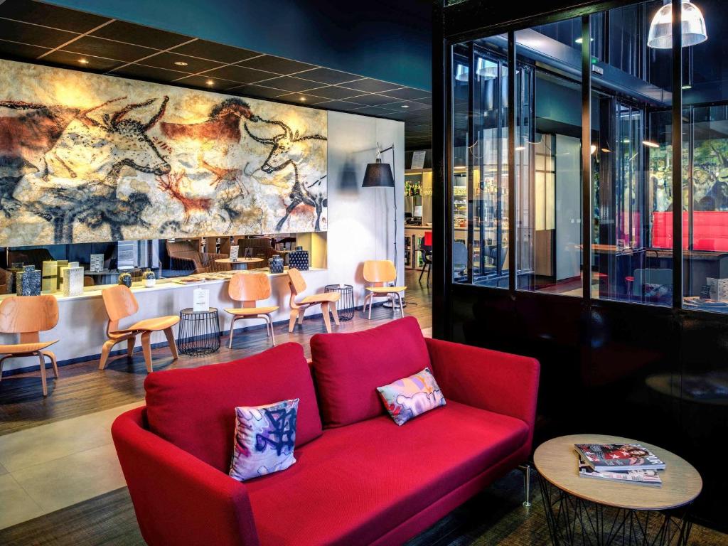 a red couch in a restaurant with a bar at Mercure Périgueux Centre Historique in Périgueux