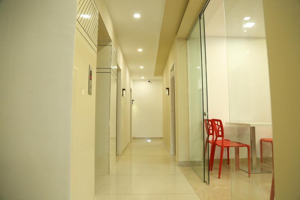 a hallway with a red chair and a table at 4U Business Hotel in Chennai