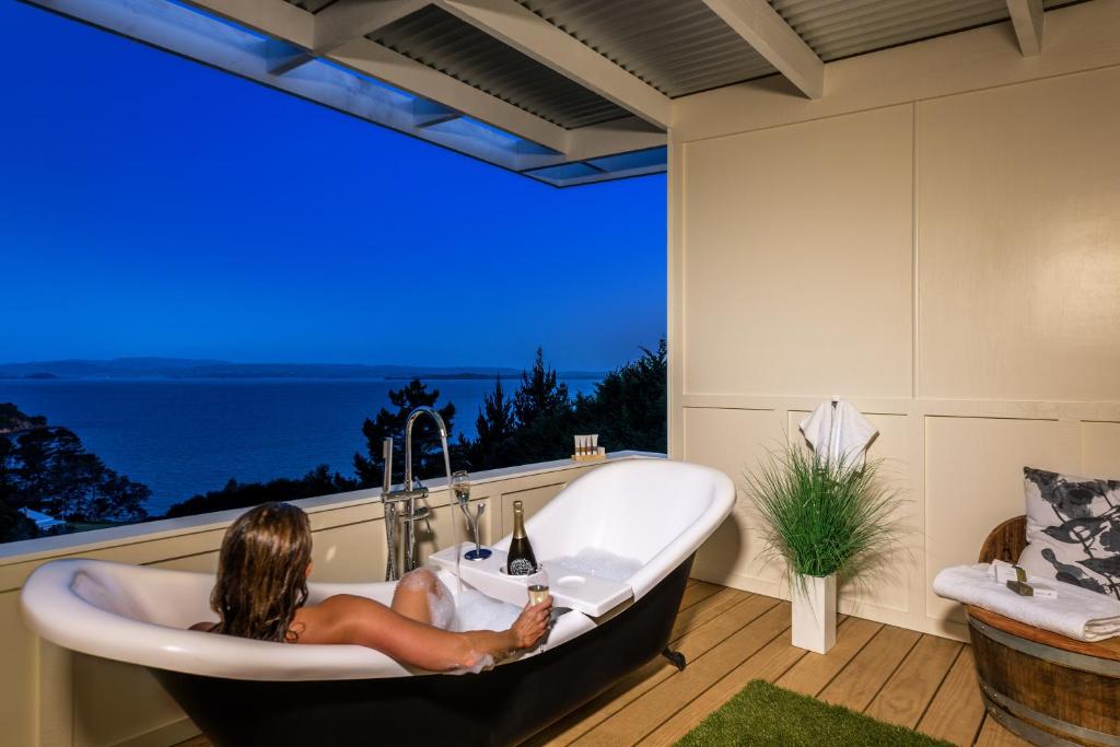 a woman sitting in a bath tub in front of a window at Woodside Bay Chalets in Ostend