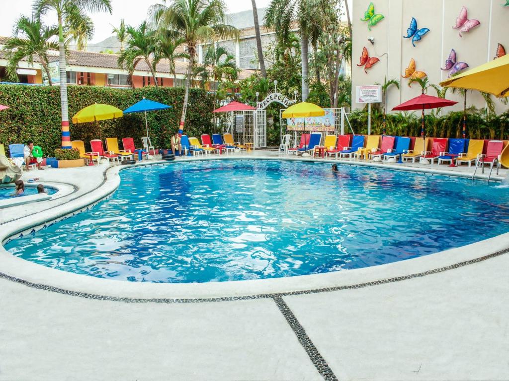 a large pool with chairs and umbrellas at a hotel at Sands Acapulco Hotel & Bungalows in Acapulco