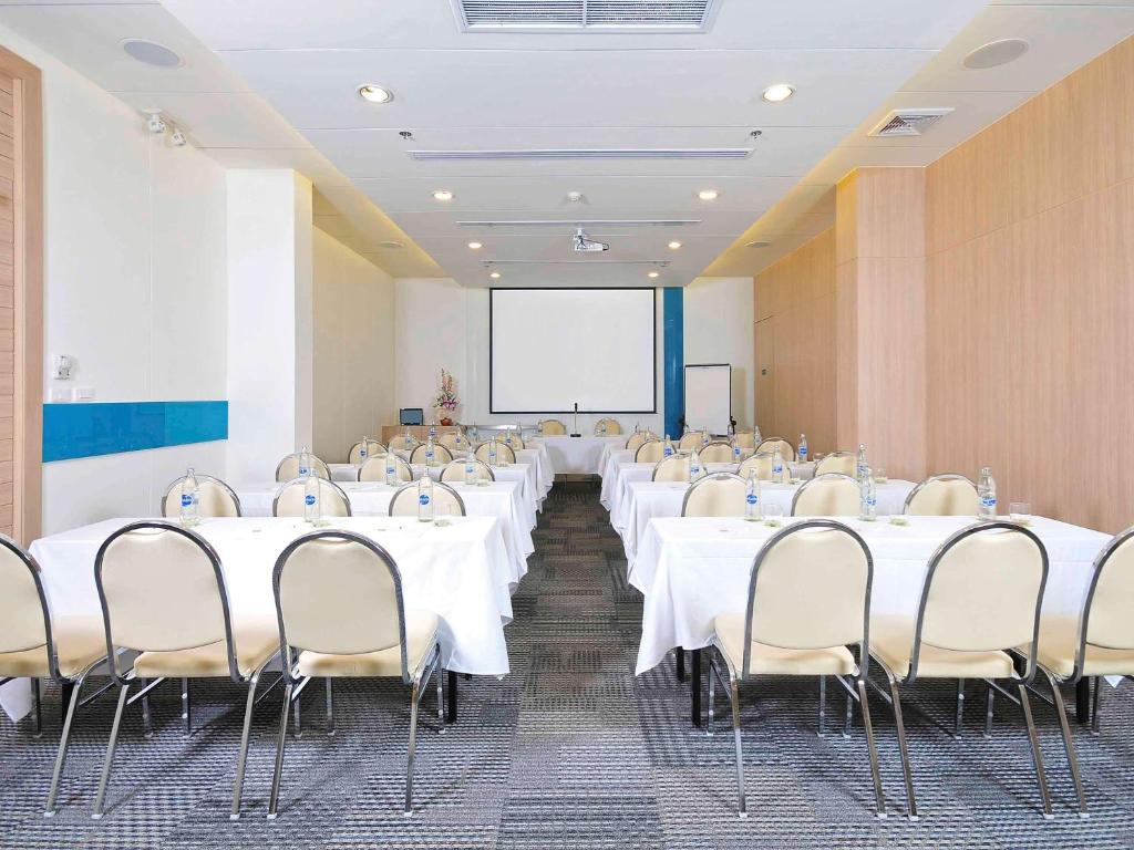 a conference room with white tables and chairs and a screen at Ibis Phuket Kata in Kata Beach