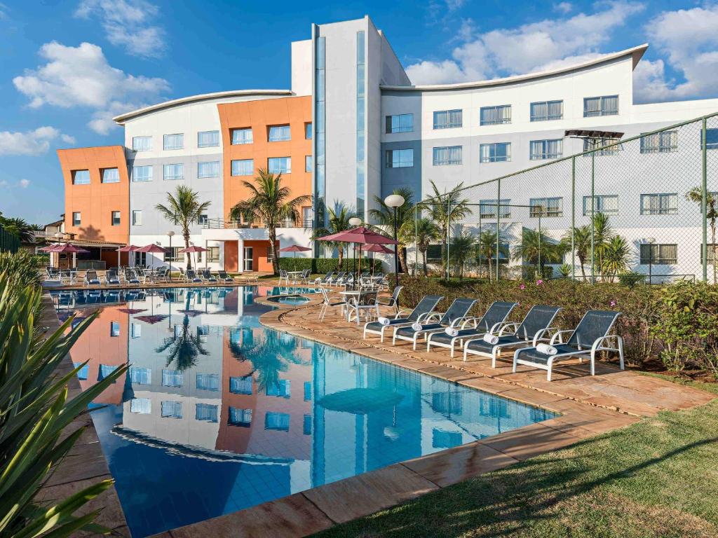 a hotel with chairs and a pool in front of a building at Transamerica Lagoa dos Ingleses in Nova Lima