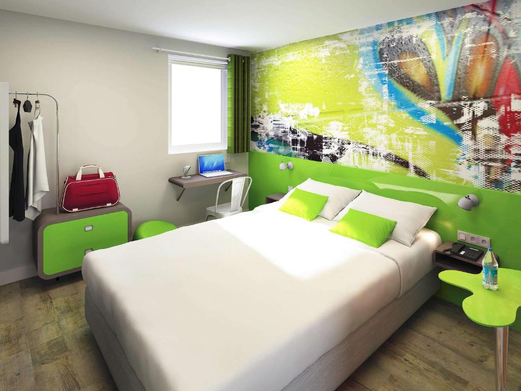 a bedroom with a large bed and a painting on the wall at Ibis Styles Lyon Villeurbanne Parc de la Tête d'Or in Villeurbanne